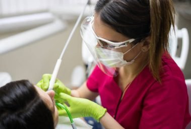 Female dentist cleaning teeth of a beautiful patient woman in dental clinic